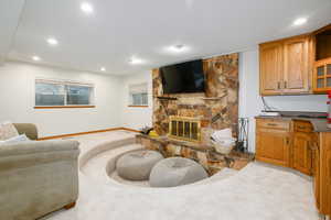 Living area featuring light colored carpet, a stone fireplace, and recessed lighting