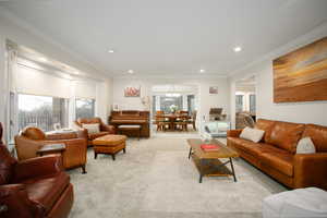 Living room featuring crown molding, light colored carpet, and a chandelier