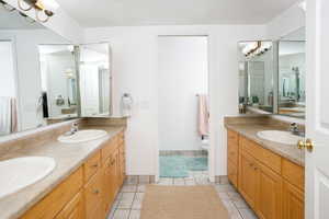 Bathroom with two vanities, a chandelier, and light tile patterned flooring
