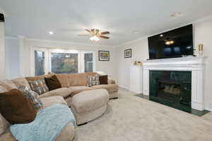 Carpeted living room featuring ornamental molding, ceiling fan, a high end fireplace, and recessed lighting