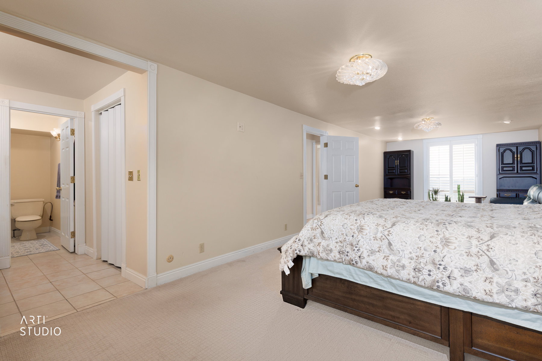 Bedroom with light colored carpet, ensuite bath, and light tile patterned floors