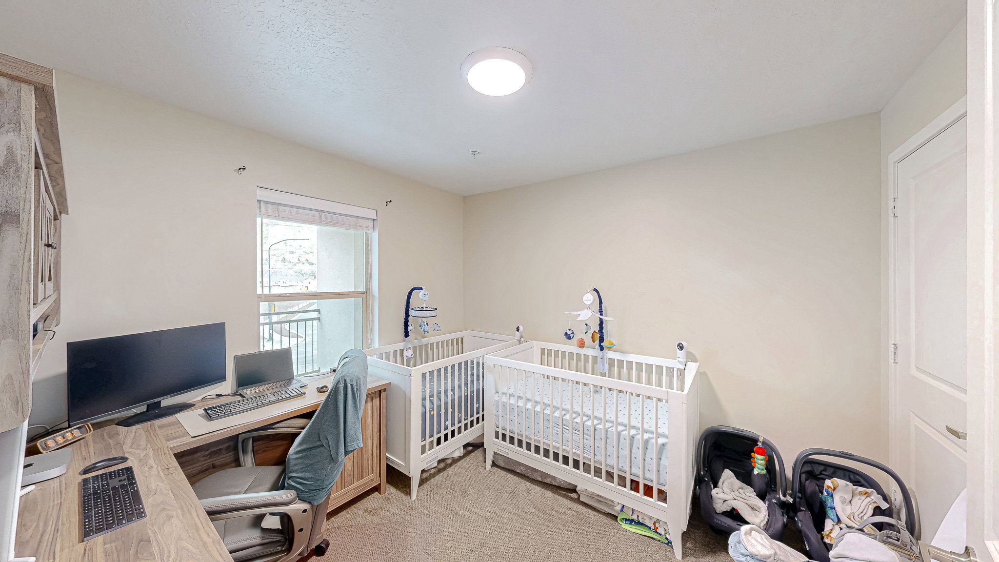 Bedroom with light colored carpet and a desk