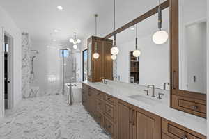 Primary Bathroom with double vanity, a walk in closet, a stall shower, and hanging lights