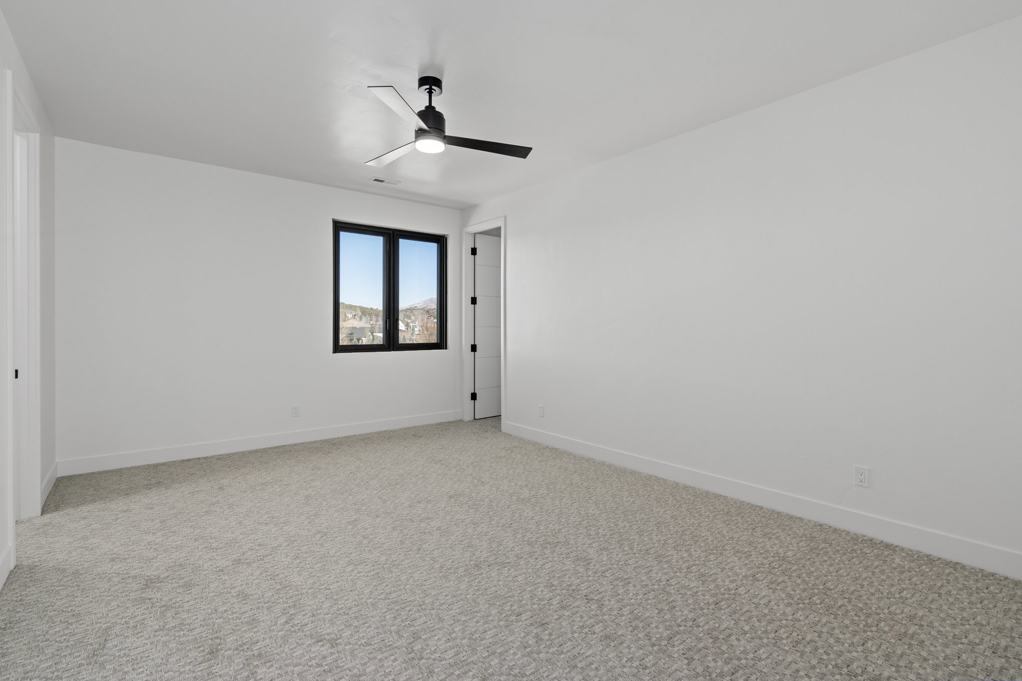 Upstairs bedroom with light carpet and ceiling fan