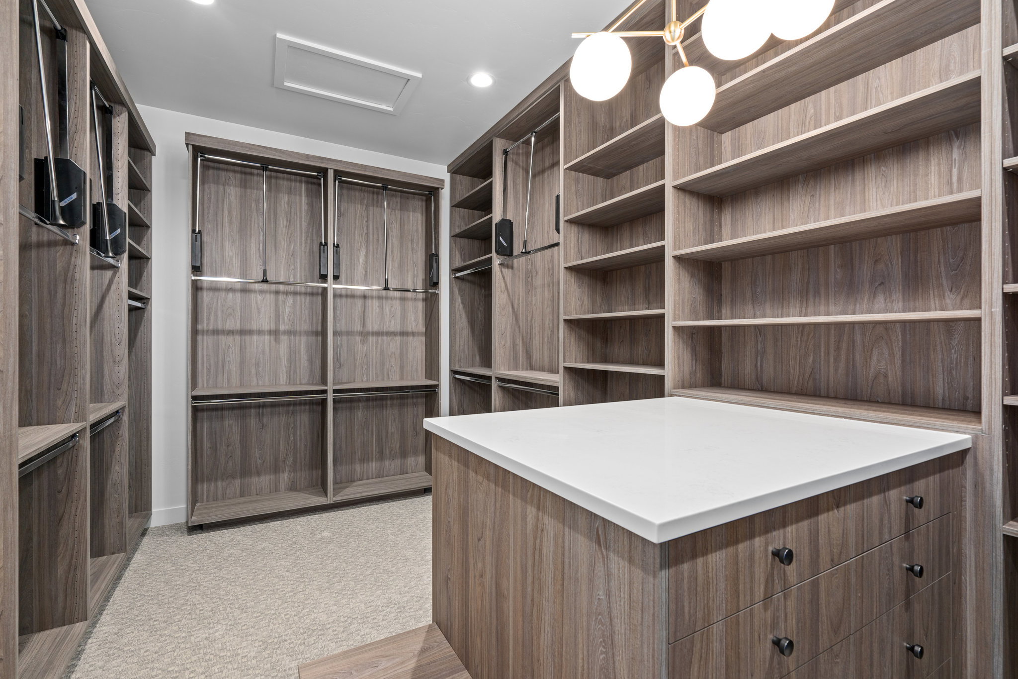 Primary Walk in closet with attic access and light colored carpet