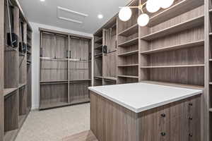 Primary Walk in closet with attic access and light colored carpet