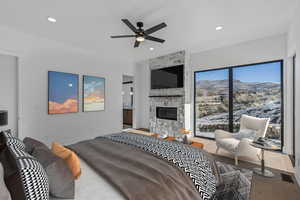 primary suite featuring ensuite bathroom, access to exterior, a fireplace, ceiling fan, and light wood-style flooring