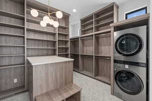 Primary suite closet Laundry area with stacked washer / dryer and hanging lights
