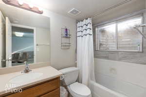 Full bathroom with vanity, shower / bath combo with shower curtain, and a textured ceiling