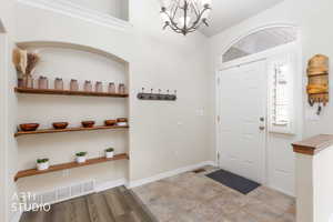 Foyer entrance with hanging lights and baseboards