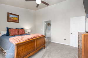 Bedroom with ensuite bathroom, light colored carpet, a ceiling fan, and a high ceiling