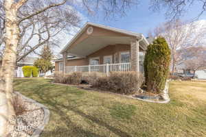 View of home's exterior with a lawn, stucco siding, a porch, and stone siding