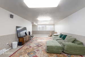 Living area featuring a textured ceiling, wainscoting, and light colored carpet