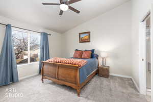 Bedroom with vaulted ceiling, light carpet, and a ceiling fan