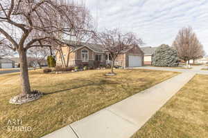 View of front of property featuring a front yard, driveway, and a garage