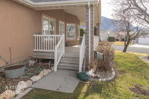 Doorway to property with stucco siding, a yard, roof with shingles, a mountain view, and covered porch