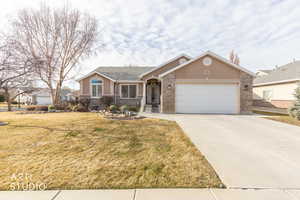 Ranch-style house featuring concrete driveway, a garage, stucco siding, a front yard, and brick siding