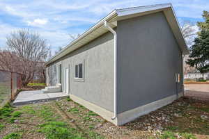 View of side of property featuring stucco siding and a patio area
