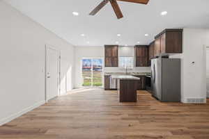 Kitchen with dark wood finish cabinetry, stainless steel appliances, a ceiling fan, a kitchen island, and recessed lighting