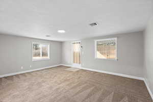 Unfurnished room featuring light carpet and a textured ceiling