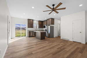 Kitchen featuring dark wood finish cabinetry, a kitchen island, stainless steel appliances, a ceiling fan, and recessed lighting
