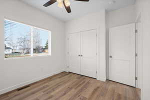 Unfurnished bedroom featuring dark wood-type flooring, a closet, and a ceiling fan