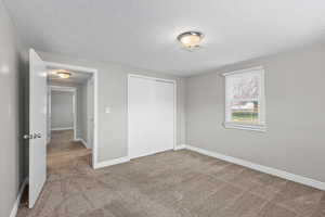 Unfurnished bedroom featuring a closet, carpet, and a textured ceiling