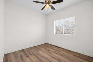 Spare room with dark wood-type flooring and ceiling fan