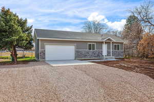 Ranch-style house with driveway, a shingled roof, stone siding, and a garage