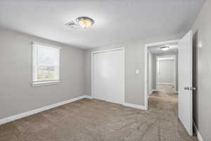 Unfurnished bedroom with carpet flooring, a closet, and a textured ceiling