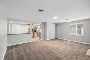 Unfurnished living room with light colored carpet and a textured ceiling