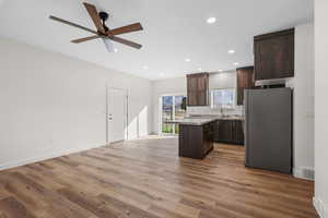 Kitchen with dark wood finish cabinetry, freestanding refrigerator, recessed lighting, a ceiling fan, and light wood finished floors