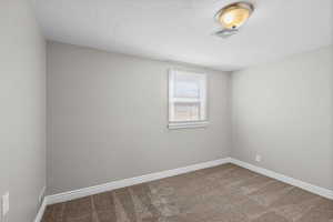 Spare room featuring carpet flooring and a textured ceiling