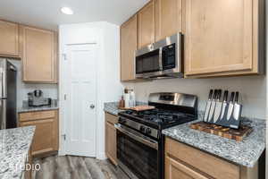 Kitchen featuring stainless steel appliances, light stone countertops, light wood-style flooring, light wood finish cabinetry, and recessed lighting