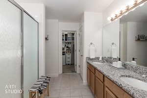 Bathroom featuring double vanity, a stall shower, light tile patterned floors, and a walk in closet