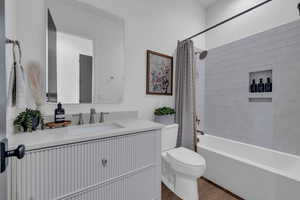 Bathroom with shower / bath combo with shower curtain, vanity, and wood finished floors
