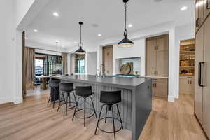 Dual tone kitchen featuring modern cabinets, built in fridge, light wood finished floors, a breakfast bar area, and dual tone cabinetry
