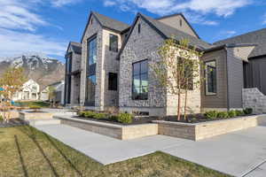 View of side of home with stone siding, a mountain view, and a yard