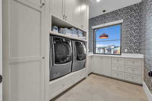 Laundry area with wallpapered walls and light tile patterned floors