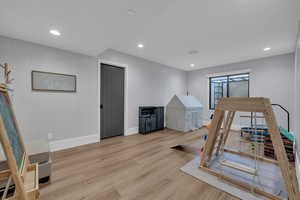Recreation room with light wood-style flooring and recessed lighting