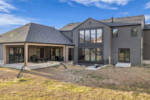 Back of property with roof with shingles and a patio area