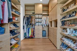 Walk in closet with light wood-style flooring