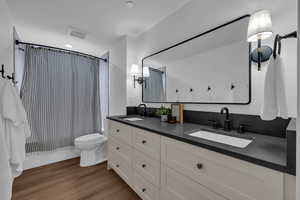 Bathroom featuring double vanity and dark wood-style flooring