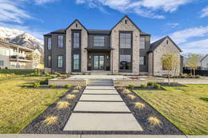 View of front facade with a mountain view, a front lawn, and stone siding