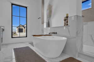 Full bathroom featuring marble tiled flooring and a freestanding bath