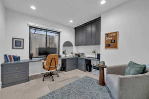 Office space with built in desk, light colored carpet, and recessed lighting