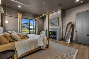 Bedroom with a glass covered fireplace, wood finished floors, and recessed lighting