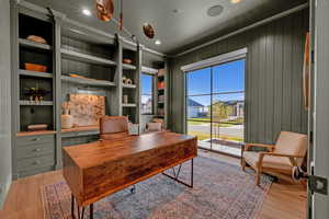 Home office with built in features, light wood finished floors, recessed lighting, and a residential view