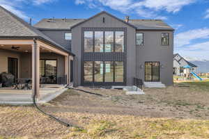 Rear view of house featuring roof with shingles, board and batten siding, a patio area, a playground, and a mountain view