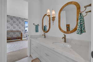 Full bathroom with double vanity, light carpet, and wallpapered walls